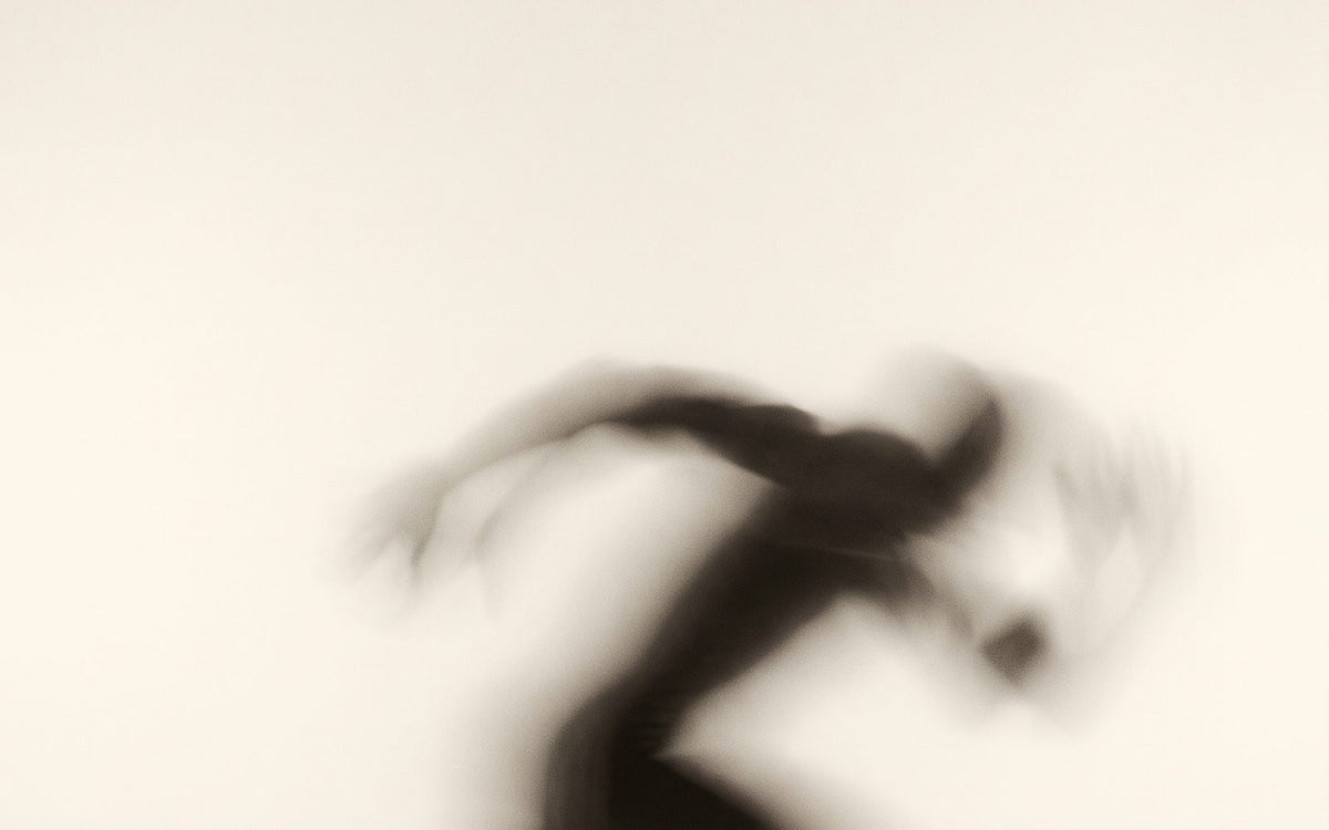 A sprinter driving out of the blocks, dissolved into motion against a cream ground
