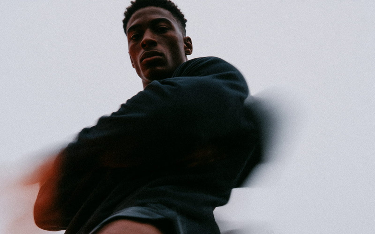 A person in a dark hooded top turning mid-movement, motion-blurred