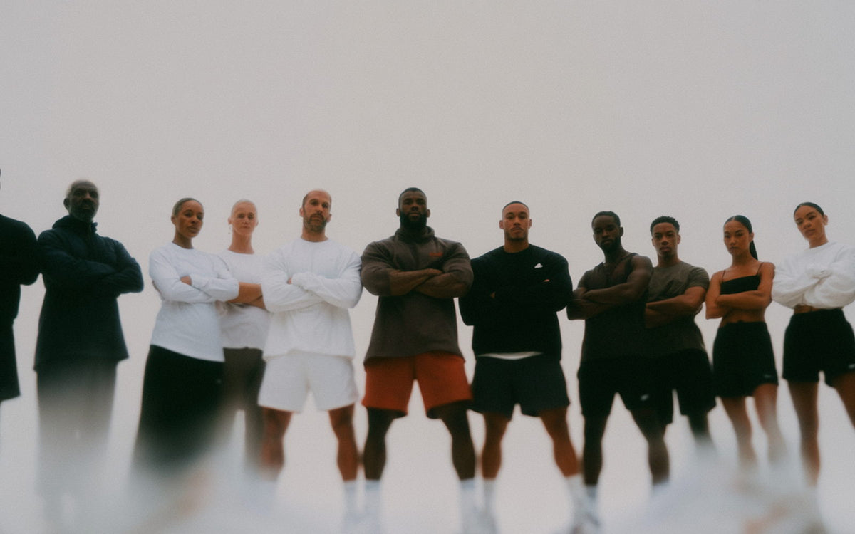 A line of people in training clothes standing against a bright wall