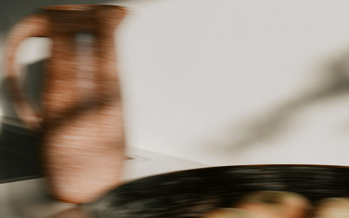 A stoneware jug and a shallow bowl on a sunlit kitchen counter