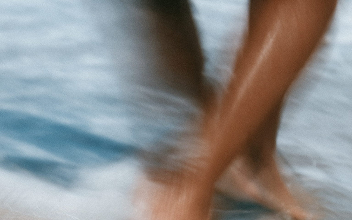 Bare feet on pale sand at the water's edge