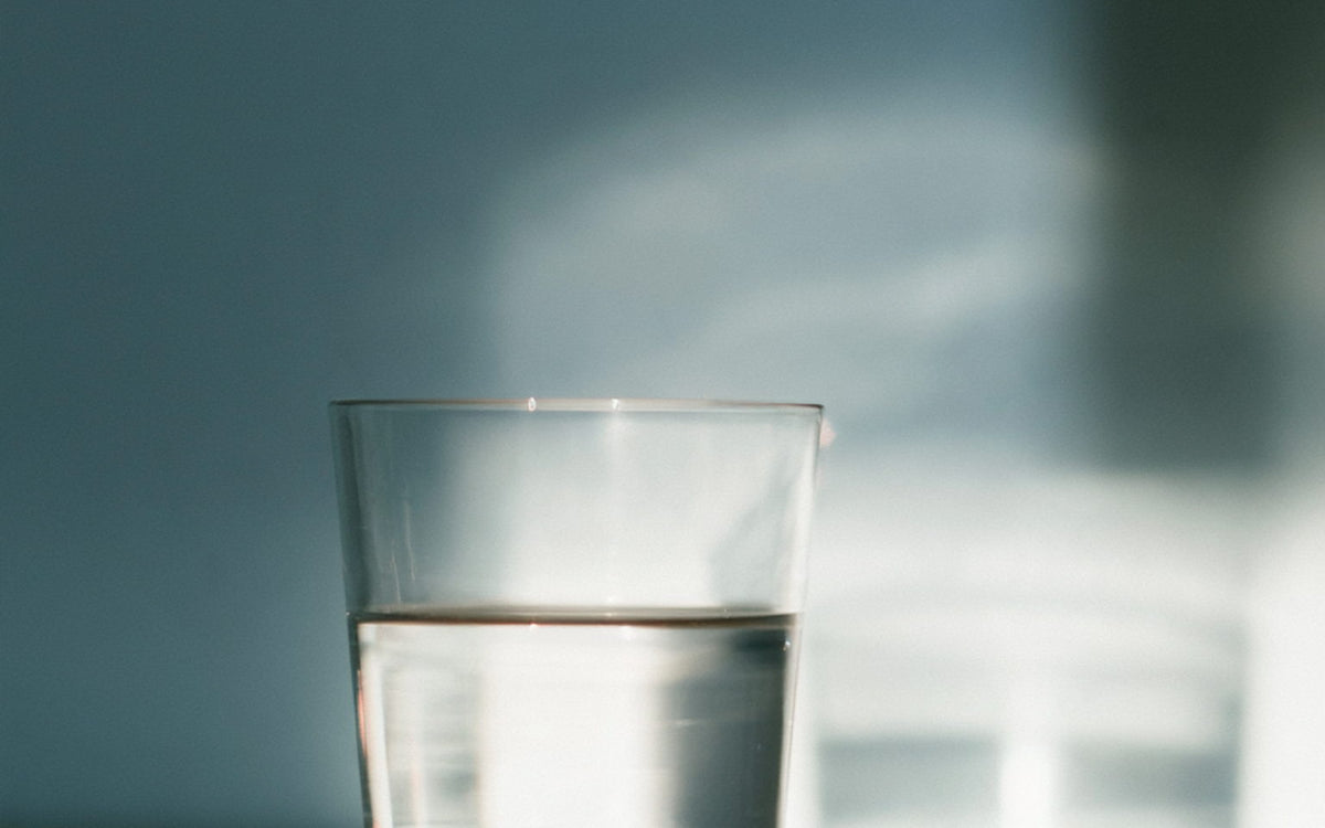 A glass of water on a white marble counter in bright light