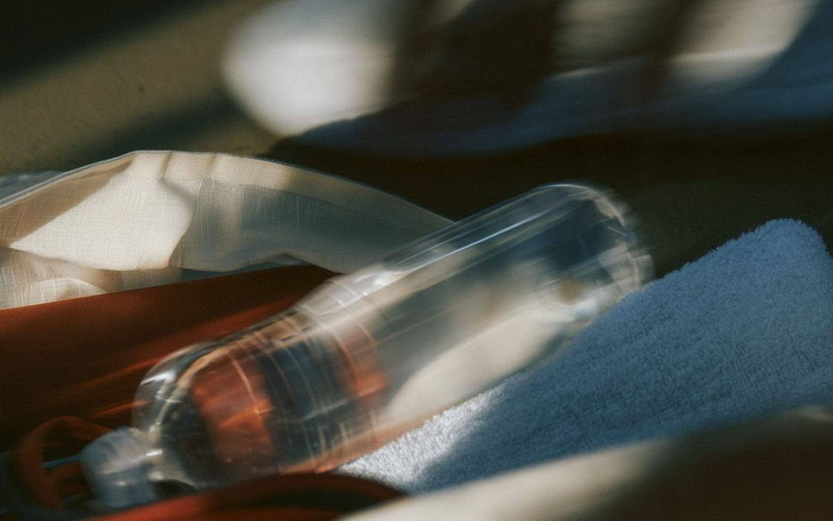 A gym bag on the floor with a water bottle and a folded towel